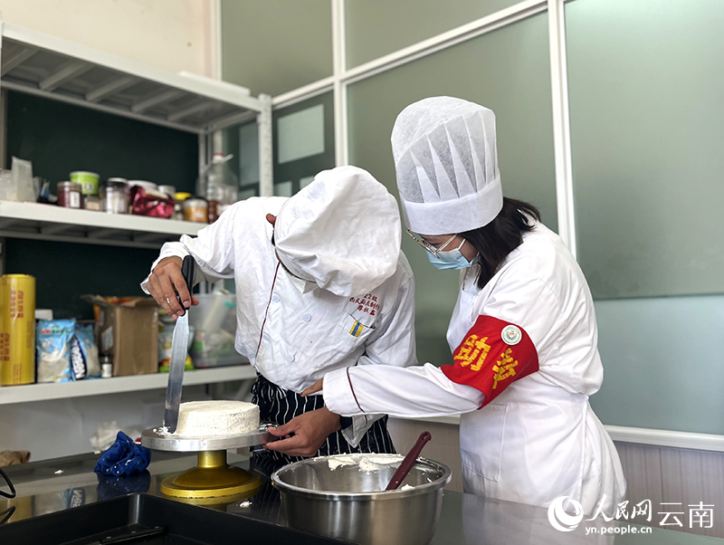 3西式面点制作实训课上，黄永灿（右）协助同学制作蛋糕。人民网-尹馨摄